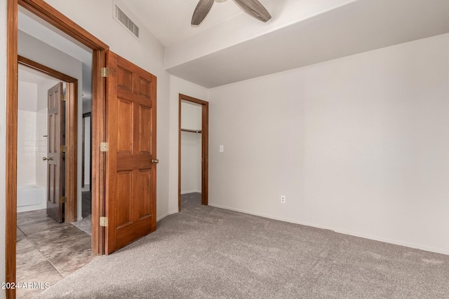 unfurnished bedroom with ceiling fan, ensuite bathroom, and light colored carpet