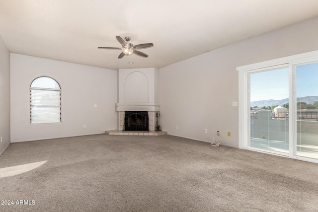 unfurnished living room with a fireplace, a mountain view, plenty of natural light, and ceiling fan