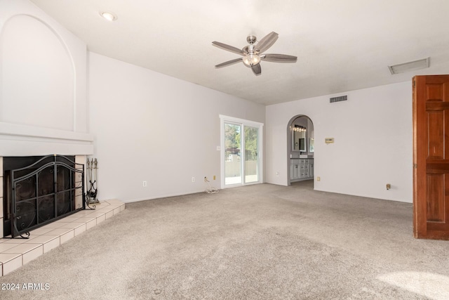 unfurnished living room with light carpet, ceiling fan, and a tiled fireplace