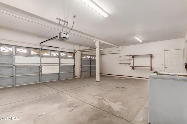 garage featuring white fridge and a garage door opener