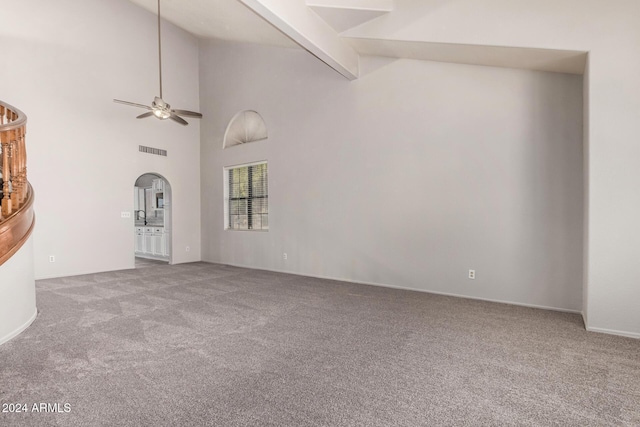 unfurnished living room featuring beamed ceiling, carpet floors, high vaulted ceiling, and ceiling fan