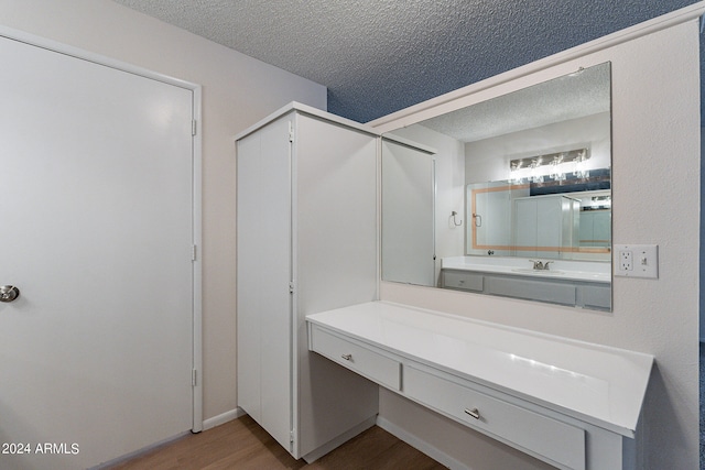 bathroom featuring a textured ceiling, wood-type flooring, and vanity