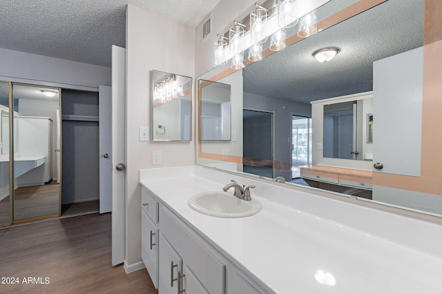 bathroom with a textured ceiling, hardwood / wood-style flooring, and vanity