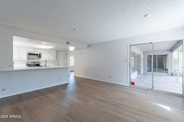 unfurnished living room featuring a textured ceiling, hardwood / wood-style floors, and sink