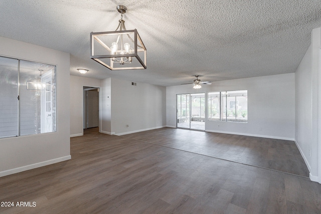 empty room with a textured ceiling, ceiling fan with notable chandelier, and dark wood-type flooring