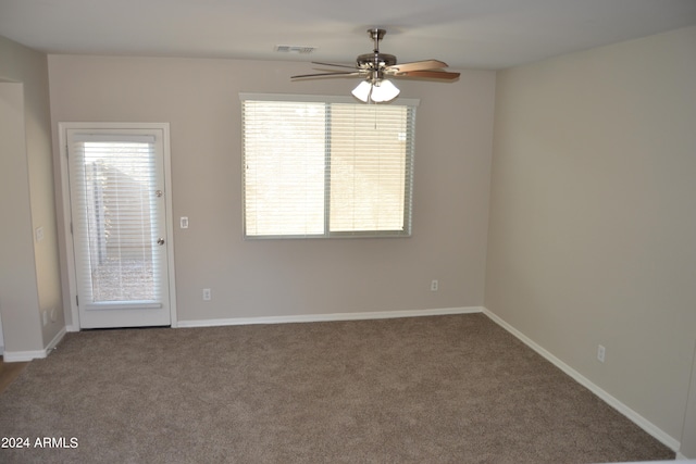 carpeted spare room featuring ceiling fan and plenty of natural light