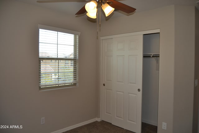 unfurnished bedroom featuring dark carpet, a closet, and ceiling fan