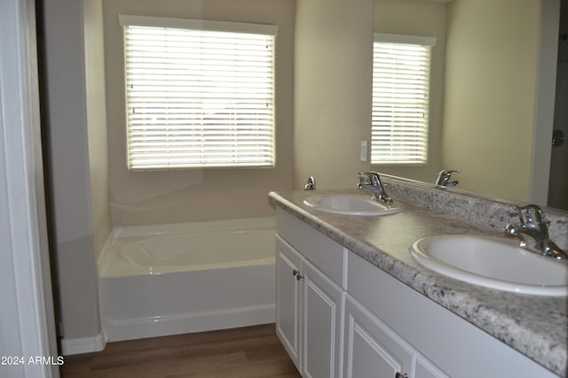 bathroom with a tub to relax in, wood-type flooring, and double vanity