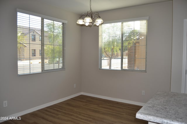 unfurnished dining area with dark hardwood / wood-style floors, a healthy amount of sunlight, and an inviting chandelier