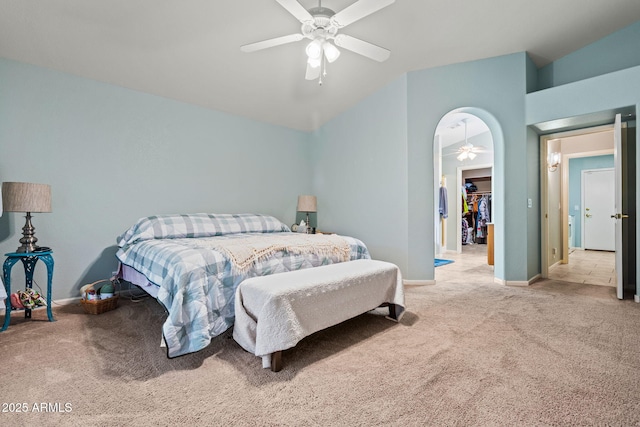 bedroom featuring lofted ceiling, a spacious closet, light carpet, a closet, and ceiling fan