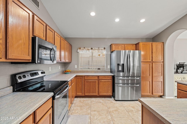 kitchen with light tile patterned floors, vaulted ceiling, and appliances with stainless steel finishes