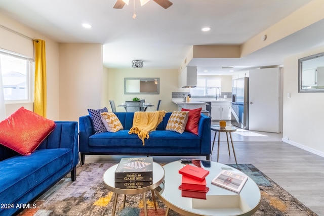 living room with light hardwood / wood-style floors, ceiling fan, and sink