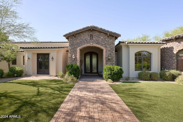 mediterranean / spanish-style home featuring french doors and a front lawn