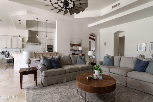 living room featuring sink, a raised ceiling, and light tile patterned floors