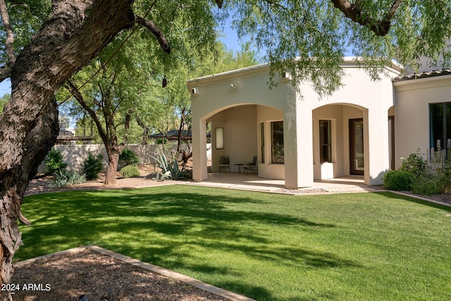 back of property with a yard and a patio