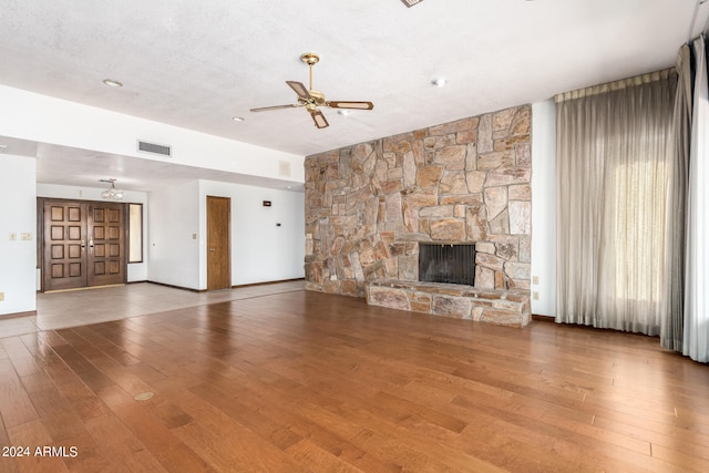 unfurnished living room featuring a textured ceiling, a fireplace, hardwood / wood-style floors, and ceiling fan