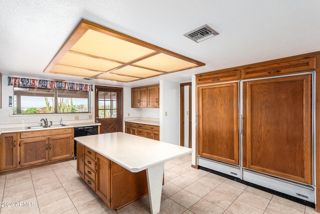 kitchen with paneled refrigerator, a textured ceiling, sink, a kitchen island, and light tile patterned floors