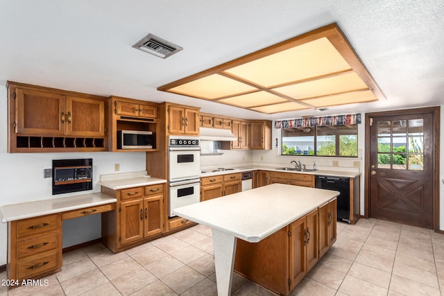 kitchen featuring light tile patterned flooring, sink, white appliances, a textured ceiling, and a center island