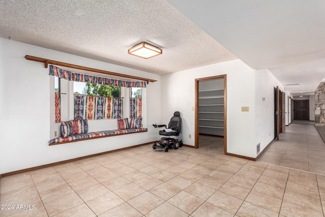 spare room with a textured ceiling and light tile patterned floors