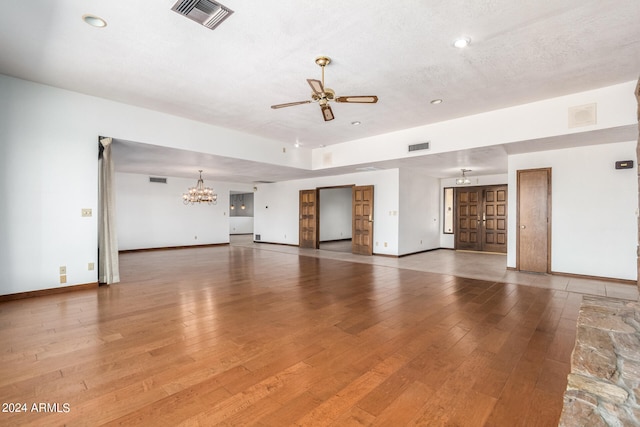 unfurnished living room featuring wood-type flooring, a textured ceiling, and ceiling fan with notable chandelier