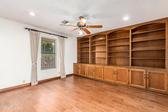 unfurnished living room with light hardwood / wood-style floors, ceiling fan, and a textured ceiling