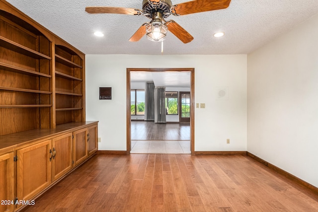 spare room featuring a textured ceiling, light hardwood / wood-style floors, and ceiling fan