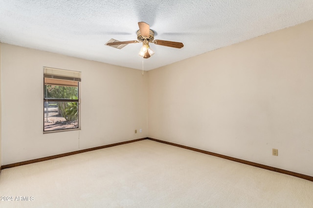 spare room with ceiling fan, light colored carpet, and a textured ceiling