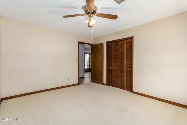 unfurnished bedroom with ceiling fan, a textured ceiling, a closet, and light carpet