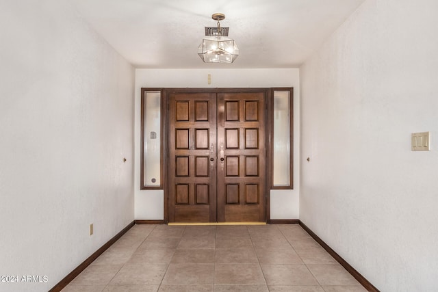 tiled foyer with a notable chandelier