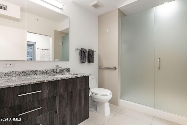 bathroom with tile patterned flooring, vanity, toilet, and a shower with door