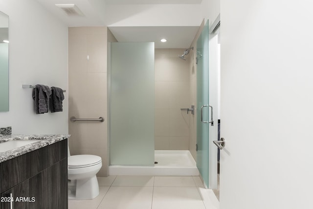 bathroom featuring tile patterned floors, vanity, toilet, and a shower with door