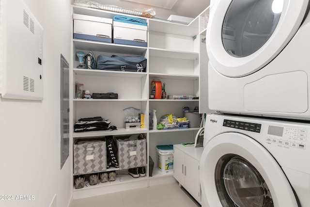 clothes washing area with light tile patterned floors and stacked washer and dryer