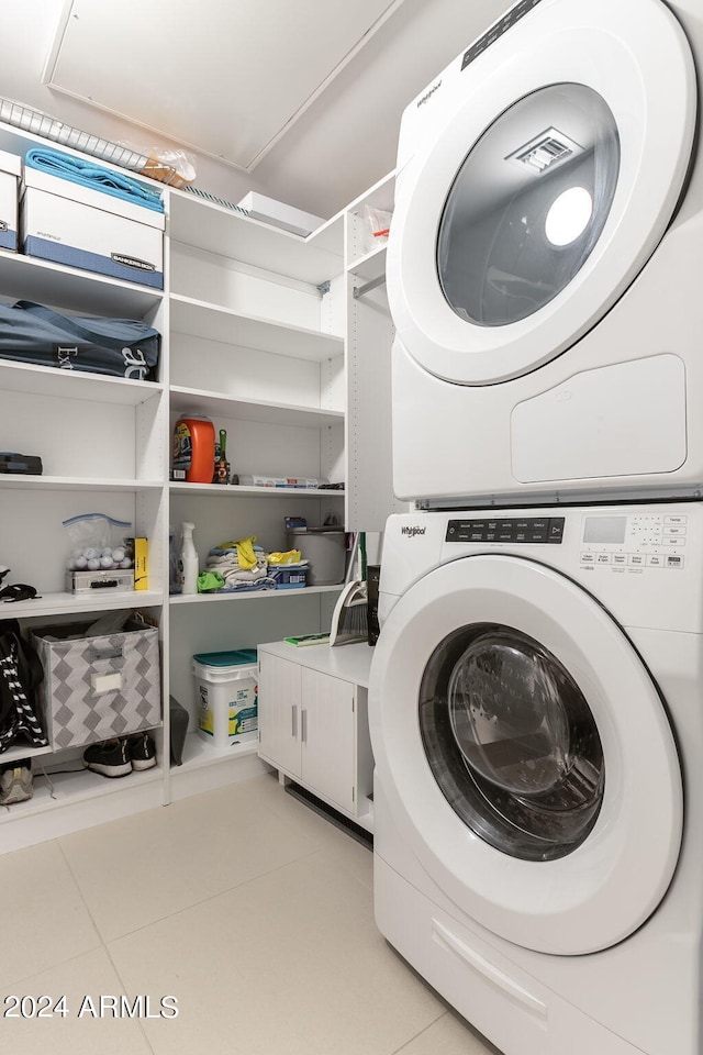 washroom with stacked washer / drying machine and light tile patterned floors