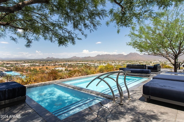 view of swimming pool featuring a mountain view, a patio area, and an in ground hot tub