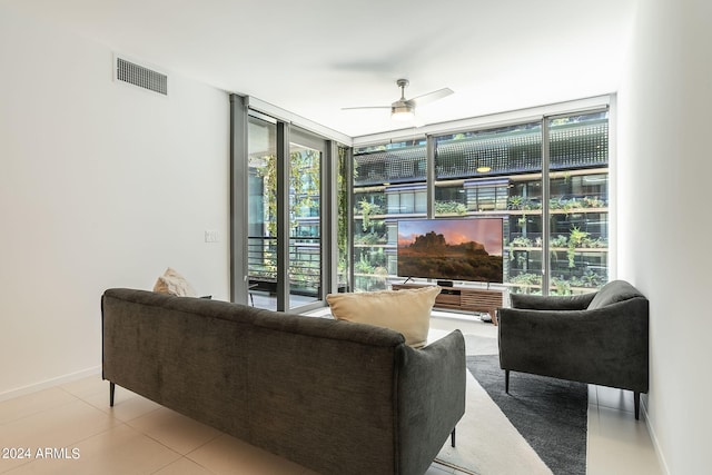 tiled living room featuring expansive windows and ceiling fan