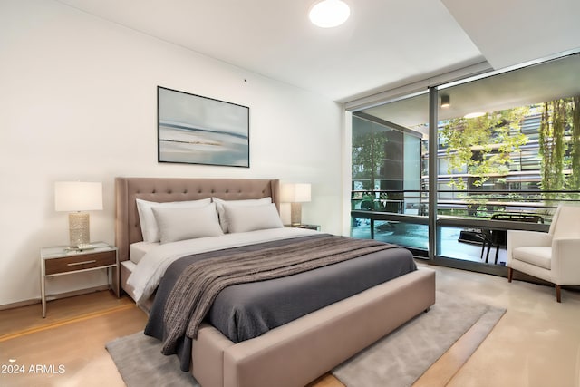 bedroom with access to outside, light hardwood / wood-style flooring, and a wall of windows