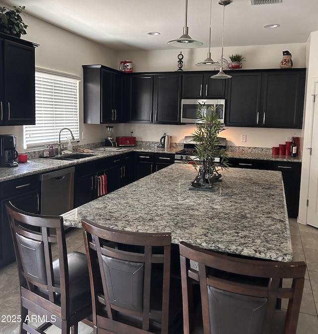 2665 E Gillcrest Rd, Gilbert, AZ 85298 - kitchen with dark cabinets, a breakfast bar, light stone countertops, appliances with stainless steel finishes, and a sink