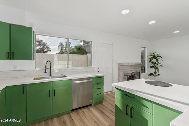 kitchen with sink, a fireplace, green cabinets, light hardwood / wood-style floors, and stainless steel dishwasher