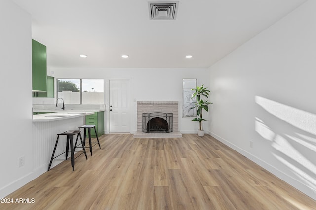 living room with sink, light hardwood / wood-style flooring, and a fireplace