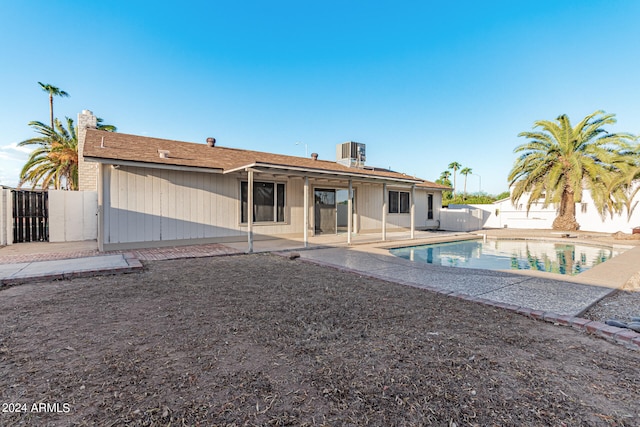 rear view of property with a patio, a fenced in pool, and central AC unit