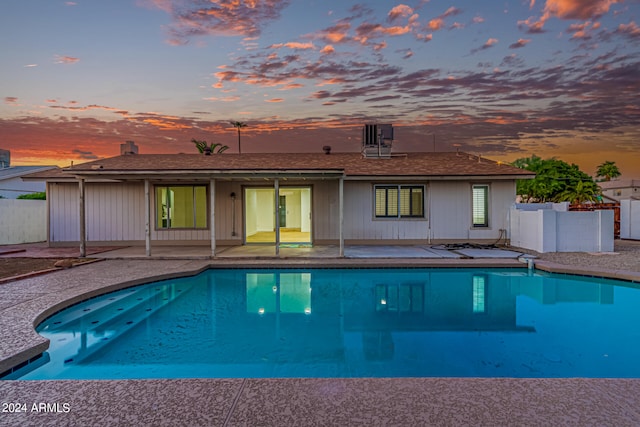 pool at dusk featuring a patio