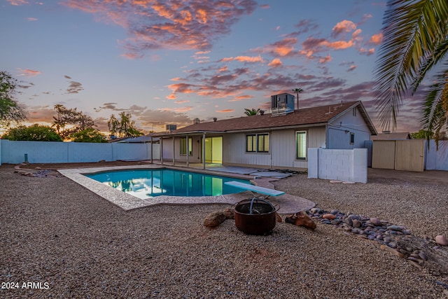 pool at dusk featuring a diving board and a patio