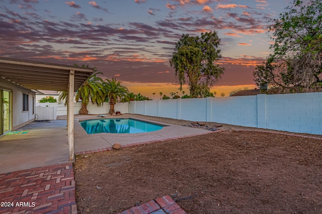 pool at dusk featuring a patio area