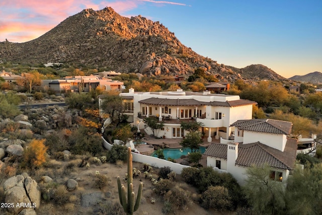 back house at dusk with a mountain view and a patio