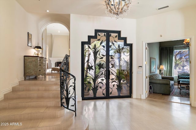 corridor featuring french doors, light tile patterned floors, and a chandelier