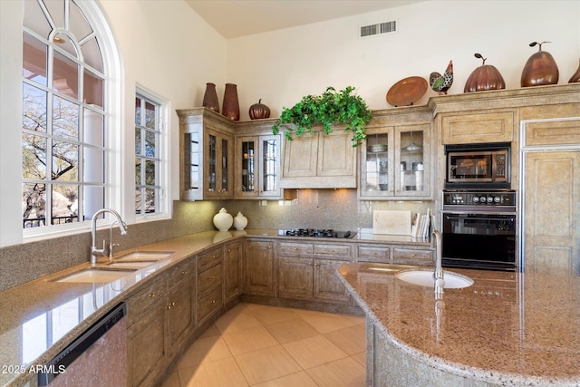 kitchen featuring light stone countertops, sink, black appliances, and tasteful backsplash