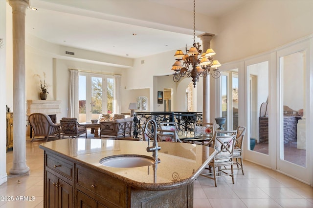 interior space featuring ornate columns, a notable chandelier, tile patterned flooring, french doors, and sink