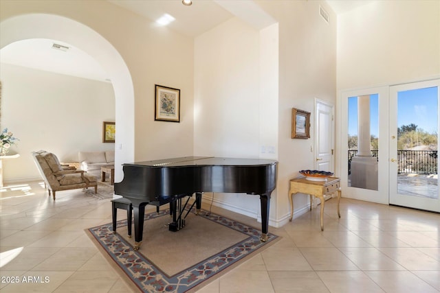 miscellaneous room with a towering ceiling, french doors, and light tile patterned flooring