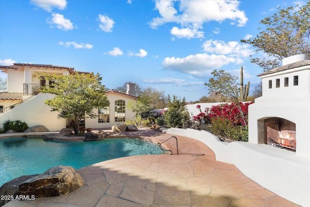 view of swimming pool with an outdoor fireplace and a patio area