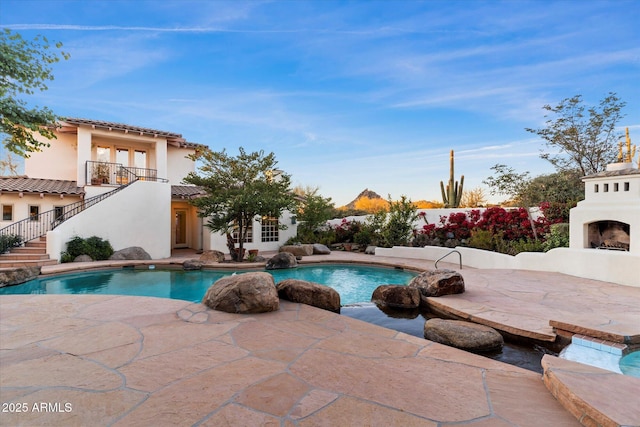 view of pool featuring an outdoor fireplace and a patio